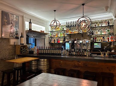 Interior de la taberna con barra y mesas de madera